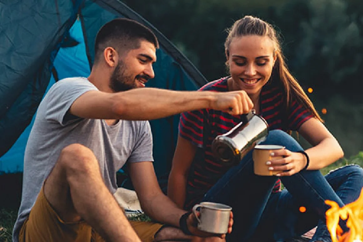 Zwei Personen trinken Kaffee am Lagerfeuer